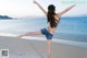 A woman standing on a beach with her arms outstretched.