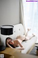 A naked woman laying on a couch next to a lamp.