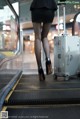 A woman walking down an escalator with a suitcase.