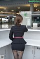 A woman in a black dress standing in front of a counter.