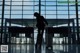 A woman walking through an airport with a suitcase.