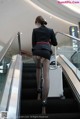 A woman in a black dress is walking down an escalator.