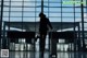 A woman walking through an airport with a suitcase.