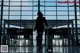 A woman walking through an airport with a suitcase.