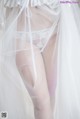 A woman wearing a white lingerie and a veil.