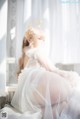 A woman in a white dress sitting on a window sill.