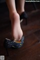 A close up of a woman's shoes on a wooden floor.