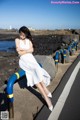 A woman in a white dress leaning against a blue railing.