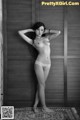 A naked woman standing in front of a wooden door.