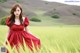 A woman in a red dress standing in a field.