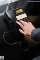 A woman's hand is pressing a button on a telephone.