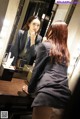 A woman in a business suit is looking at herself in the mirror.