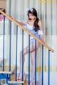 A woman in a blue and white dress is standing on the stairs.