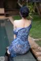 A woman in a blue dress sitting by a pool.