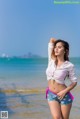 A woman standing on a beach next to the ocean.