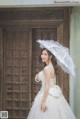 A woman in a wedding dress holding an umbrella.