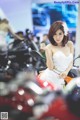 A woman in a white dress sitting on a motorcycle.