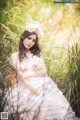 A woman in a pink dress sitting in tall grass.