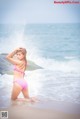 A woman in a pink bikini sitting on the beach.