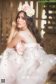 A woman in a pink dress sitting on a hay bale.