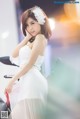 A woman in a white dress sitting on a motorcycle.