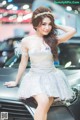 A woman in a silver dress posing on a car.