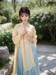 A woman in a yellow and blue hanfu is posing for a picture.