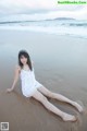 A woman in a white dress laying on the beach.