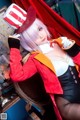 A woman in a red and white top hat sitting on a chair.