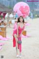 A woman in a pink dress standing on a beach.