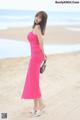 A woman in a pink dress standing on a beach.