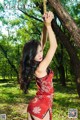 A woman in a red dress hanging from a tree.