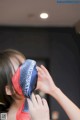 A woman putting a red and blue bandana on her face.