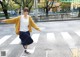 A woman in a yellow jacket is standing on a crosswalk.