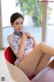 A woman sitting on a red chair in a room.