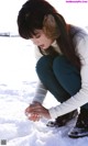 A woman crouching down in the snow with her hands on the ground.