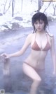 A woman in a bikini sitting in a hot spring.