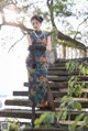 A woman in a blue and orange dress standing on some steps.