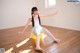 A young ballerina sitting on a yellow ball in a room.