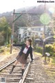 A woman in a school uniform is standing on a train track.