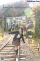 A woman in a school uniform is standing on a train track.