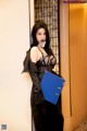 A woman in a black dress holding a blue folder.