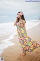 A woman in a colorful dress standing on a beach.