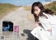 A woman in a white dress sitting on a dirt road.