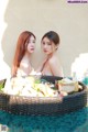 A couple of women sitting next to each other near a pool.