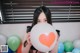 A woman holding a large white balloon with a red heart on it.