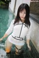 A woman in a white shirt and black stockings standing in a pool.