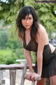 A woman in a black dress leaning on a wooden railing.