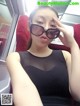 A woman in a black dress and sunglasses on a train.