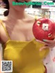 A woman in a yellow dress holding a red apple.